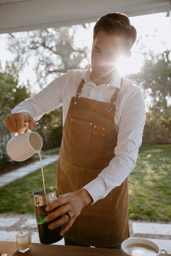 Homegrown barista pouring milk into an iced coffee in the afternoon light