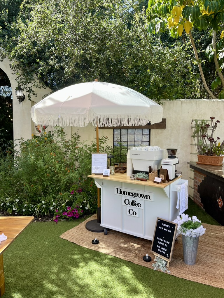 Homegrown coffee cart set up in a garden beneath a white umbrella
