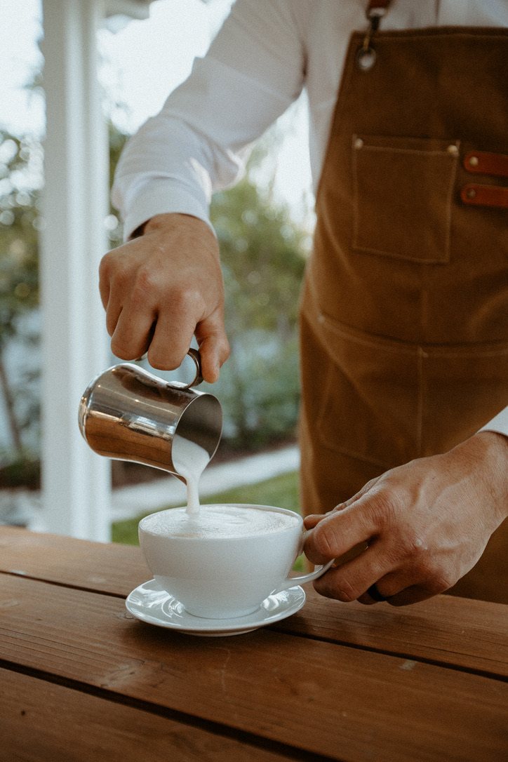 A Homegrown barista finishing a latte with steamed milk