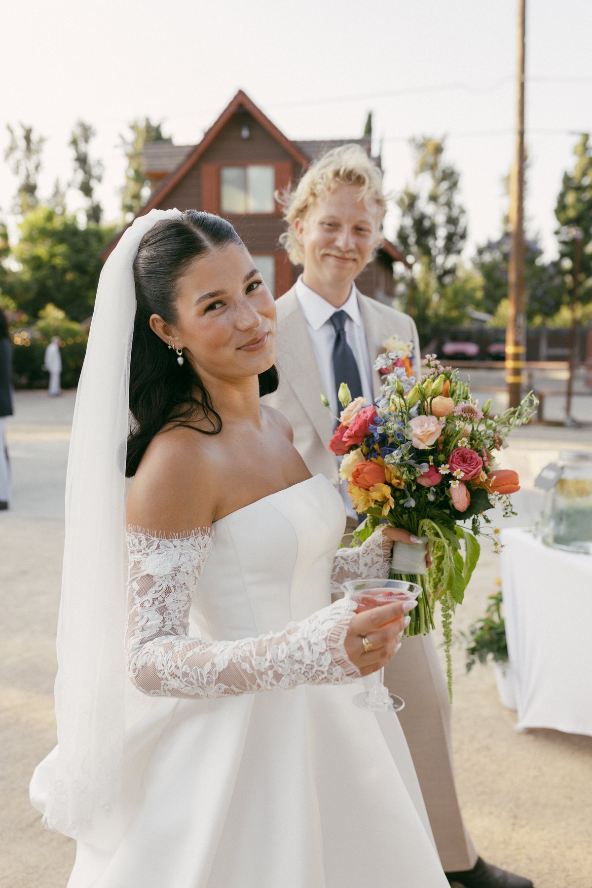 Bride holding a colorful bouquet with the groom beside her
